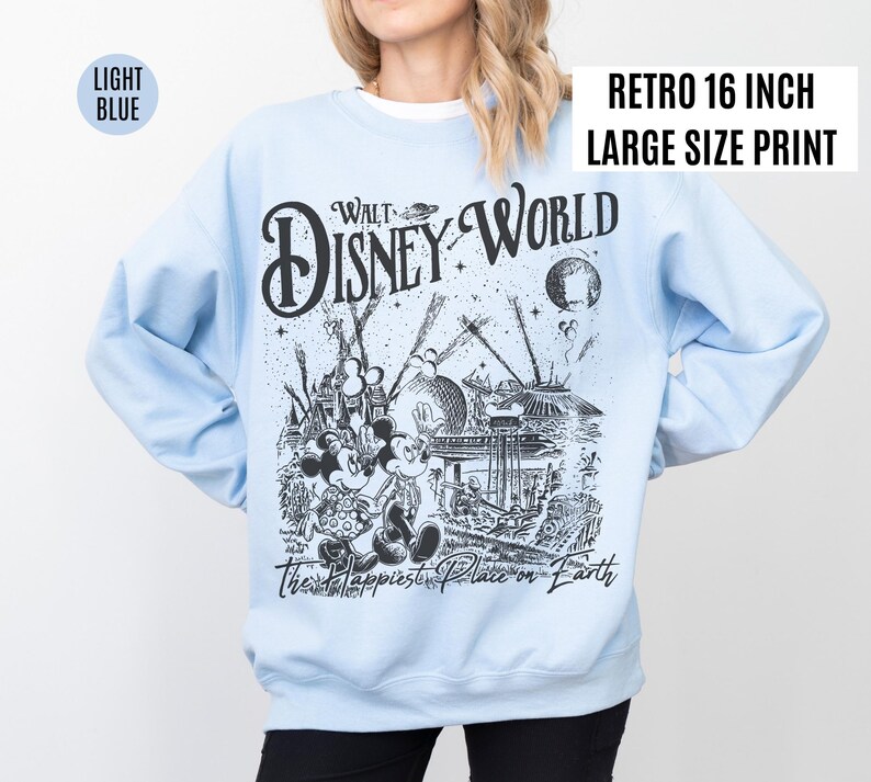 Peut inclure: Sweat-shirt bleu clair avec un imprim&eacute; graphique r&eacute;tro de Walt Disney World. Le motif noir et blanc repr&eacute;sente Mickey et Minnie Mouse, des attractions du parc et le texte "The Happiest Place on Earth". L'impression est de grande taille.