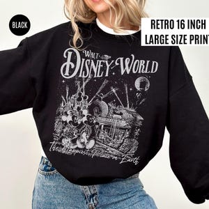 Peut inclure: Sweat-shirt noir avec une impression graphique r&eacute;tro de Walt Disney World. Le design pr&eacute;sente les mots "Walt Disney World" et "The Happiest Place on Earth" avec une impression de grande taille de 40.6 cm.
