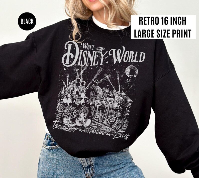 Peut inclure: Sweat-shirt noir avec une impression graphique r&eacute;tro de Walt Disney World. Le design pr&eacute;sente les mots "Walt Disney World" et "The Happiest Place on Earth" avec une impression de grande taille de 40.6 cm.