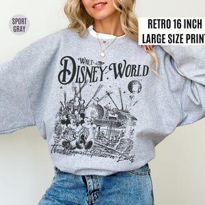 Peut inclure: Un sweat-shirt gris clair avec un graphisme noir et blanc de Walt Disney World, avec Mickey et Minnie Mouse. Le texte "Walt Disney World" et "The Happiest Place on Earth" sont affich&eacute;s. Le sweat-shirt a le texte "Retro 16 inch Large Size Print".
