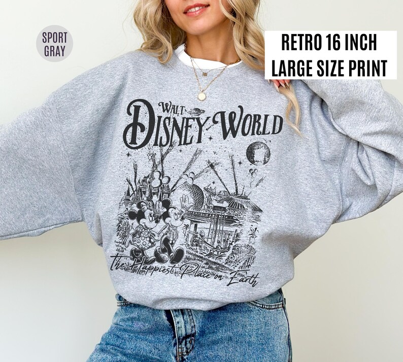 Peut inclure: Un sweat-shirt gris clair avec un graphisme noir et blanc de Walt Disney World, avec Mickey et Minnie Mouse. Le texte "Walt Disney World" et "The Happiest Place on Earth" sont affich&eacute;s. Le sweat-shirt a le texte "Retro 16 inch Large Size Print".