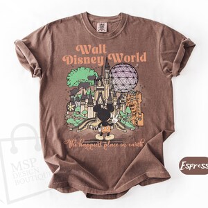 May include: Espresso-colored t-shirt featuring a graphic of Walt Disney World with Mickey Mouse. The design includes a castle, Spaceship Earth, and the text "Walt Disney World" and "The happiest place in earth".