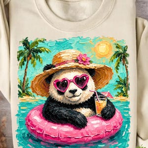 May include: A cream-colored sweatshirt featuring an impasto-style graphic of a panda wearing a straw hat with a pink flower and heart-shaped sunglasses. The panda is in a pink inner tube in blue water with palm trees, a sun, and a drink.