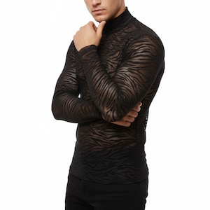 May include: Black long-sleeved turtleneck shirt with a zebra stripe pattern. The sheer fabric reveals the skin underneath. The shirt has a high neckline and a fitted silhouette, suitable for layering or as a statement piece.