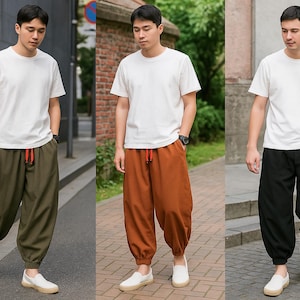 May include: Three men wearing white t-shirts and loose-fitting pants in olive green, rust, and black. The pants have a drawstring waist and are paired with white slip-on shoes. The outfits are casual and comfortable.