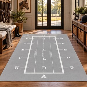 Könnte beinhalten: Ein rechteckiger grauer Teppich mit einem weißen Dressurviereck-Diagramm. Das Design umfasst weiße Begrenzungslinien, gestrichelte Viertellinien, eine Mittellinie sowie die in Weiß aufgedruckten Buchstaben A, K, V, E, S, H, C, M, R, B, P, F, G, I, X, L und D.