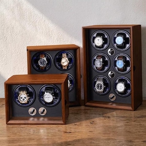 May include: Three wooden watch display cases of varying sizes. Each case has a dark wood finish and features rotating watch holders with blue accents. Several watches with leather and metal bands are displayed inside the cases.