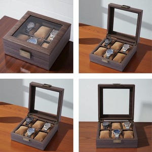 May include: A dark brown wooden watch display case with a glass top, showcasing six individual compartments with tan cushions. The case has a rectangular shape and a metal clasp. Several watches are visible inside the case.