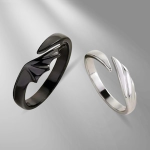 May include: Two adjustable rings. One is black with a bat wing design, the other is silver with a pointed, curved design. Both rings have an open design.