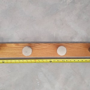 May include: A wooden coat rack with three silver hooks. The rack is approximately 20 inches long.