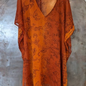 May include: A sheer orange and brown paisley print kaftan with a V-neckline and short sleeves.