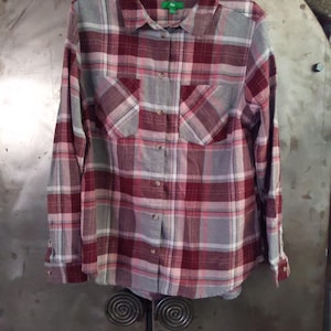 May include: A long-sleeved plaid shirt with a button-down front. The shirt is red, pink, and gray with a white plaid pattern. The shirt has two chest pockets and a green "Gap" label on the collar.