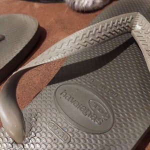 May include: A pair of brown flip-flops with the brand name "havaianas" and the size "37-38" printed on the sole.