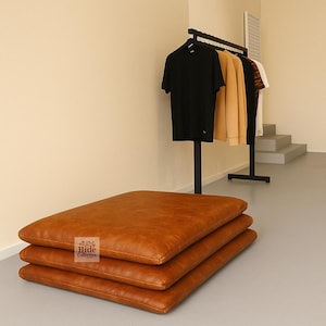 May include: A white ceramic mug with a black handle and the text "But First, Coffee" in a black, handwritten-style font. The mug is on a white surface.