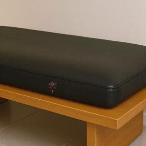 May include: A white ceramic mug with a black handle and the text "But First, Coffee" in a bold, black font. The mug is set against a blurred background, suggesting a cozy setting.