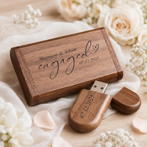 Puede incluir: Una caja rectangular de madera y una memoria USB de madera a juego. La caja está grabada con el texto Shannon & Adam engaged y la fecha 07.12.2025 junto a un corazón. La memoria USB tiene grabada la fecha 07.12.2025 y cuenta con una tapa.