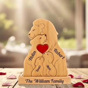 Op de afbeelding: Houten familiesculptuur met een leeuwenfamilie met een rood hart. De namen Helin, Robert, Louis en Ana zijn op de sculptuur gegraveerd. De basis luidt "The William Family".
