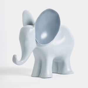 Op de afbeelding: Een lichtgrijze keramische olifantenfiguur met grote, lichtblauwe oren. De olifant heeft een gebogen slurf en vier stevige poten. De figuur is effen van kleur en staat op een witte achtergrond.