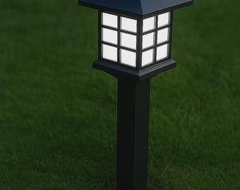 May include: A black outdoor solar-powered lantern with a square, grid-like light panel. The lantern has a pagoda-style top and is mounted on a tall, black post. The background is green grass.