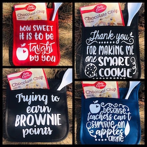 May include: Four different oven mitts with pockets for a box of chocolate chip cookie mix. The mitts are red, black, blue, and black. The text on the mitts reads: "How sweet it is to be taught by you", "Thank you for making me one smart cookie", "Trying to earn brownie points", and "Because teachers can't survive on apples alone".