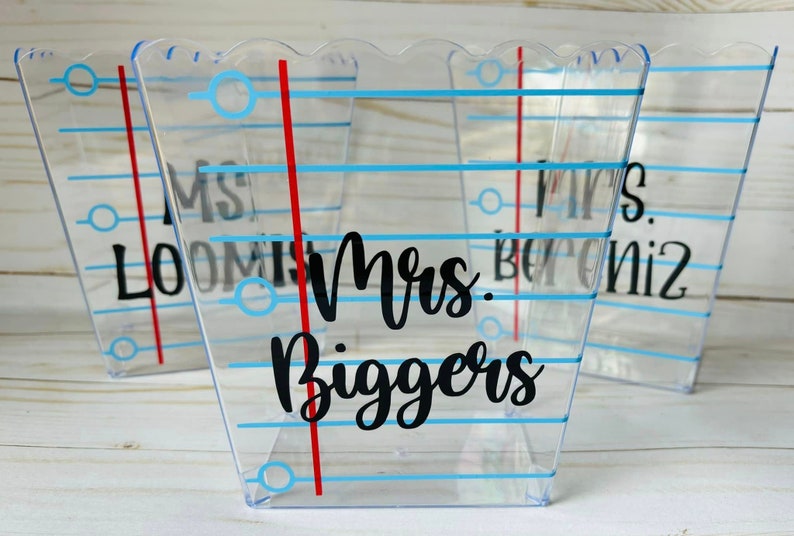 Puede incluir: Tres recipientes de pl&aacute;stico transparente con l&iacute;neas azules y rojas y fondo blanco. Los recipientes tienen los nombres "Sra. Loomis", "Sra. Biggers" y "Sra. Beroniz" escritos en ellos.