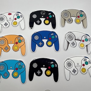 Puede incluir: Nueve pegatinas de controladores de GameCube de colores. Los controladores son de varios colores, incluyendo blanco, negro, naranja, azul y gris. Cada pegatina tiene un contorno blanco y presenta los botones y la disposición del joystick.