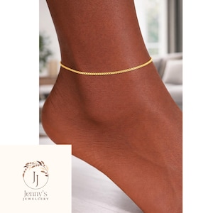May include: A fine gold anklet featuring a box chain design. The anklet is displayed on an ankle, highlighting its understated elegance. This piece of jewellery is a delicate accessory.
