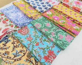 Puede incluir: Una colección de cuadrados de tela doblados que presentan varios patrones florales de estampado en bloque en colores vibrantes, incluyendo amarillo, azul, verde, rosa y naranja. Cada pieza muestra intrincados motivos botánicos con tallos, hojas y flores.