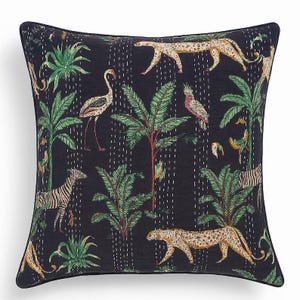 May include: Square throw pillow with a dark blue background featuring a jungle scene. The design includes zebras, leopards, flamingos, parrots, and palm trees in shades of green, tan, and white. The pillow has a black border.
