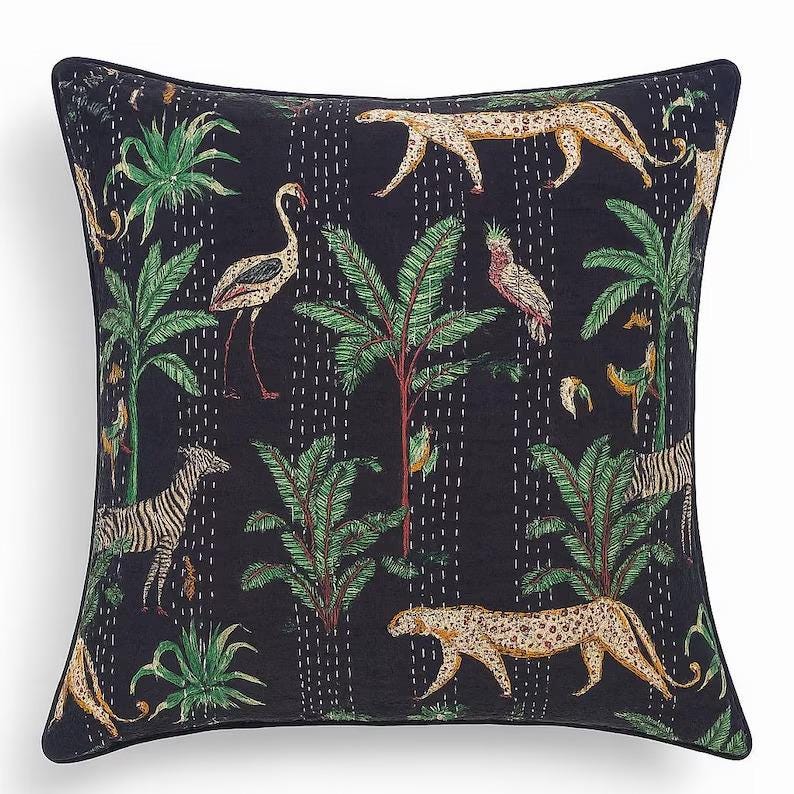 May include: Square throw pillow with a dark blue background featuring a jungle scene. The design includes zebras, leopards, flamingos, parrots, and palm trees in shades of green, tan, and white. The pillow has a black border.