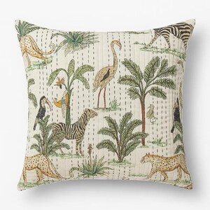 May include: Square decorative pillow with a cream background featuring a jungle scene. The design includes zebras, leopards, birds, and palm trees in shades of green, brown, and yellow. The pillow has a quilted texture with vertical stitch lines.