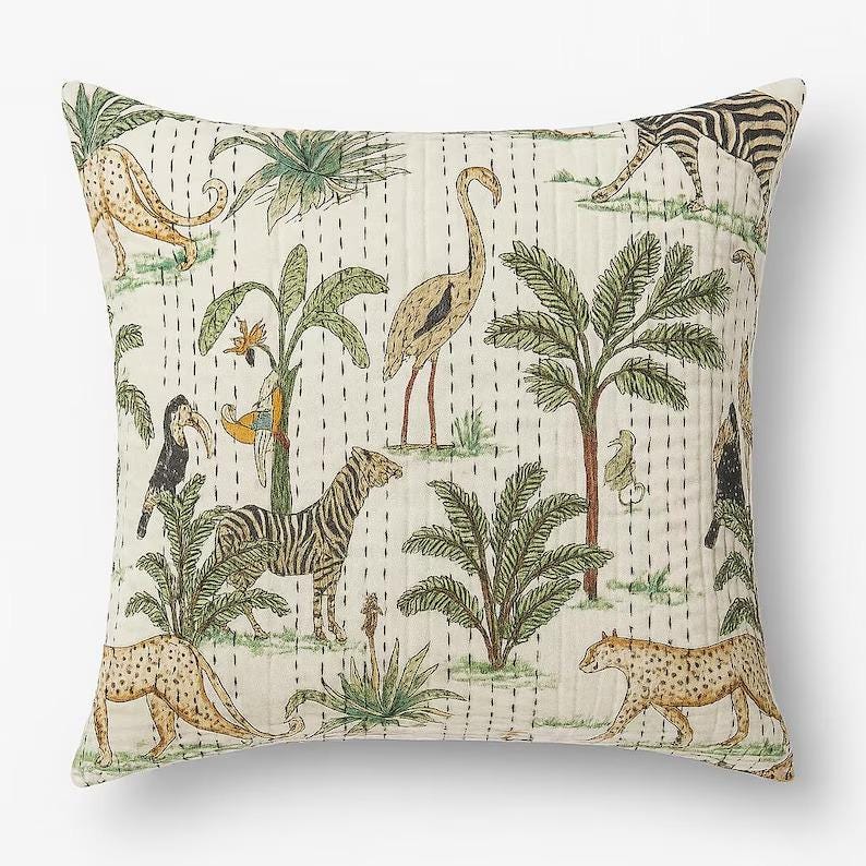 May include: Square decorative pillow with a cream background featuring a jungle scene. The design includes zebras, leopards, birds, and palm trees in shades of green, brown, and yellow. The pillow has a quilted texture with vertical stitch lines.