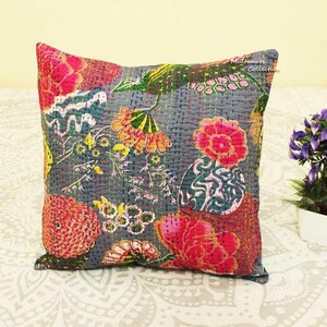 May include: A square decorative pillow with a floral design. The pillow features a gray background with embroidered flowers in shades of pink, orange, green, and yellow. The pillow has the text "Midtomare Collection" in the upper right corner.