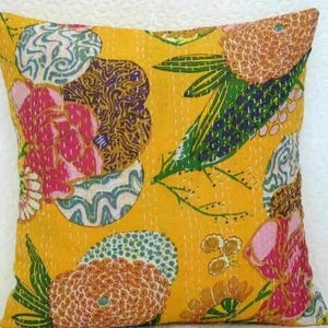 May include: A square decorative pillow with a bright yellow background. The pillow features a floral pattern with pink, brown, green, and blue accents. The design is stitched onto the fabric.