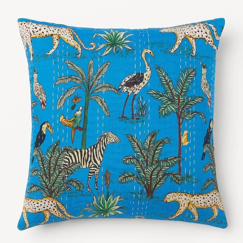 May include: Square throw pillow with a vibrant blue background featuring a jungle scene. The design includes zebras, leopards, birds, and palm trees. The pillow has a quilted texture with white stitching, adding a handcrafted feel.