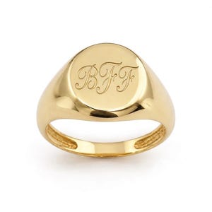 Könnte beinhalten: Ein polierter Siegelring aus Gold mit einer glatten, runden Oberfläche. In die Mitte des Rings sind die Buchstaben BFF in einer dekorativen, geschwungenen Schreibschrift eingraviert. Die Ringschiene ist aus massivem Gold mit glänzendem Finish.