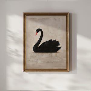 May include: A framed artwork featuring a black swan with a red beak. The swan is depicted in a realistic style against a neutral background. The frame is gold-colored, adding a touch of elegance to the piece.