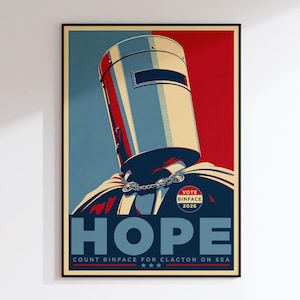 Puede incluir: Un póster rectangular que presenta una ilustración estilizada de una figura con un casco de cubo metálico y una capa. El fondo está dividido en secciones azul y roja. El texto incluye VOTE BINFACE 2026, HOPE y COUNT BINFACE FOR CLACTON ON SEA.
