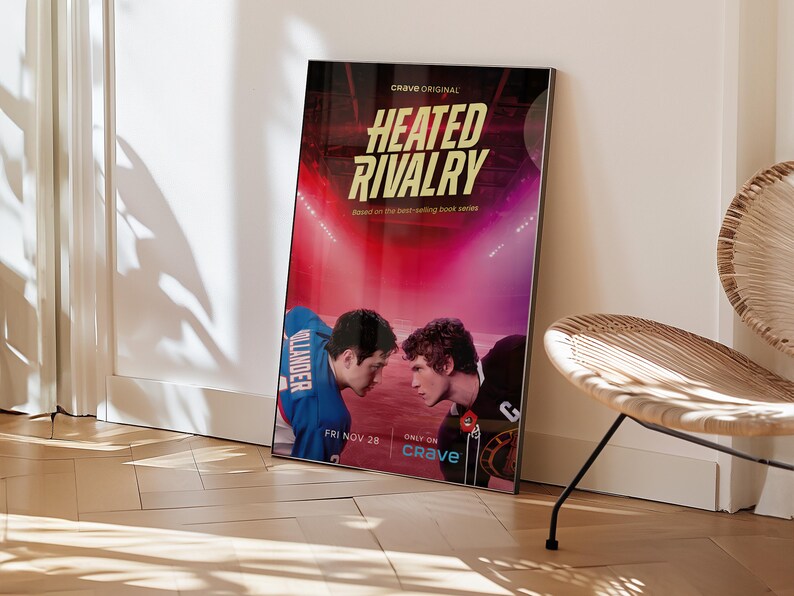 May include: A framed poster for "Heated Rivalry" leans against a wall. The poster features two young men facing each other, with the title in large, bold letters. The background is a stadium scene with red and purple hues. The text "Crave Original" is at the top.
