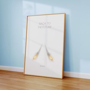 Puede incluir: Un cuadro enmarcado con el texto "BACK TO THE FUTURE" y un gráfico de dos líneas convergentes con estelas de fuego. La impresión también incluye el texto "88 MPH". El marco es de color dorado.