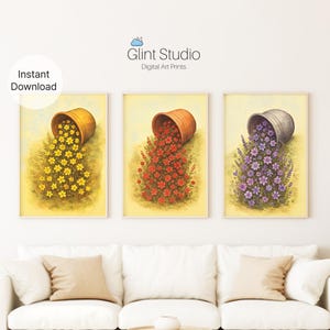 Puede incluir: Conjunto de tres impresiones artísticas digitales que representan macetas volcadas derramando flores. Una maceta derrama flores amarillas, otra rojas y la tercera moradas. Las impresiones tienen un estilo suave de acuarela con un fondo amarillo claro. El texto "Glint Studio Digital Art Prints" es visible.