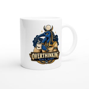 Puede incluir: Una taza de cerámica blanca con un gráfico de una deidad de estilo egipcio con cabeza de pájaro, sosteniendo una taza humeante con un icono de luna creciente. Debajo, una pancarta muestra el texto OVERTHINKING SINCE DAWN en letras negritas.
