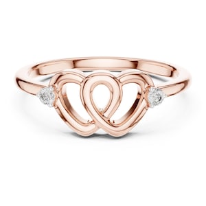 May include: Rose gold ring with two interlocking heart designs, each with a small, round diamond. The ring has a slender band and a polished finish, suitable for a romantic gift or daily wear.
