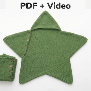 Puede incluir: Una manta de punto color verde oliva con forma de estrella, con capucha y una fila de cuatro botones marrones en un lado. El texto PDF + Video aparece en la parte superior. Se ve una sección doblada de la misma tela verde con botones.