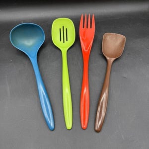 May include: A set of four kitchen utensils including a blue ladle, a lime green slotted spoon, a red four-tined fork, and a brown spatula. Each utensil features a smooth, solid-colored handle and a functional head designed for food preparation.