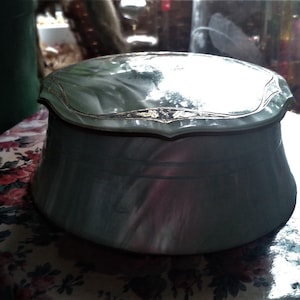 May include: A vintage green and white trinket box with a gold trim and a swirl pattern. The box has a hinged lid and is made of plastic.