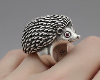May include: A silver hedgehog ring with detailed quills and a small red gem for an eye. The ring is a unique piece of jewelry, showcasing a whimsical animal design. The ring is worn on a finger.