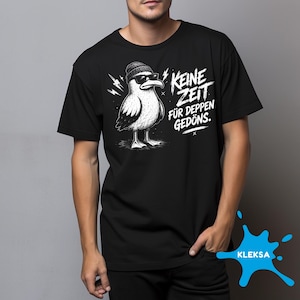 Peut inclure: Un t-shirt noir à manches courtes avec une illustration graphique blanche représentant une mouette portant un bonnet et des lunettes de soleil. Le texte "KEINE ZEIT FÜR DEPPEN GEDÖNS" est imprimé en blanc à côté de la mouette avec des éclairs.