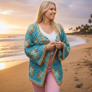 May include: A turquoise crochet cardigan with orange accents. The open-front cardigan features a square pattern design and bell sleeves. The garment is worn over a white top and pink pants, with a beach background.