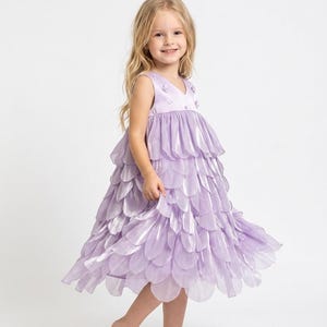 May include: A light purple dress with a layered, petal-like skirt. The sleeveless bodice has a V-neck and small floral embellishments. The dress is designed for a child and is suitable for special occasions.